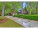 Long driveway leading to a two-car garage of brick home nestled among mature trees and landscaped grounds at 104 Huckleberry Ln, Summerville, SC 29485