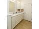 Bright bathroom with double sinks, quartz countertop, white cabinets, and wood-look tile flooring at 135 Pier View # 305, Charleston, SC 29492