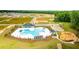 Expansive aerial view featuring a community pool, amenity center, playground, and serene pond amid lush greenery at 158 Yarrow Way, Moncks Corner, SC 29461