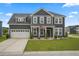 Charming two-story home boasts a well-manicured lawn, attached garage, and welcoming front porch with an American flag at 180 Basket Grass Ln, Summerville, SC 29486
