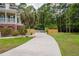 Long concrete driveway leads to a charming two-story home, enhanced by a palm tree and surrounded by a wooden fence at 187 Pecan Dr, Summerville, SC 29483