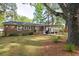 Backyard with a brick house, pergola, patio set, grill, lush lawn, and mature trees, perfect for outdoor enjoyment at 2158 Till Rd, Charleston, SC 29414