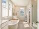 Bright bathroom featuring a soaking tub, double windows, and a glass enclosed shower at 2383 Lenwick Hall Ln, Johns Island, SC 29455