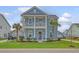 Charming two-story home with a light blue exterior, double porches, and lush landscaping at 2383 Lenwick Hall Ln, Johns Island, SC 29455