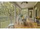 The covered porch has wooden flooring, a dining table, and views to the trees at 2856 Claybrook St, Johns Island, SC 29455