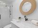 A modern bathroom features a glass shower, a woven mirror, and a white vanity with a stone countertop at 301 Hidden Bottom Ln, Daniel Island, SC 29492