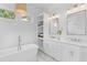 Elegant bathroom with a soaking tub, double vanity, and woven light fixture at 301 Hidden Bottom Ln, Daniel Island, SC 29492
