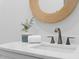 Stylish bathroom vanity with a bronze faucet, a round mirror, a white marble countertop, and greenery at 301 Hidden Bottom Ln, Daniel Island, SC 29492