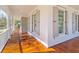 Cozy front porch with wood flooring, white columns and railings, and several windows with grey shutters at 301 Hidden Bottom Ln, Daniel Island, SC 29492