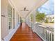 Spacious front porch with wood flooring, white columns and railings, and a ceiling fan overlooking the neighborhood at 301 Hidden Bottom Ln, Daniel Island, SC 29492