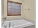 Bright bathroom with a white soaking tub and a window with decorative bamboo blinds at 311 Old Stone Ct, Moncks Corner, SC 29461