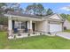 Inviting home exterior showcasing a covered porch with seating and a two car garage, surrounded by greenery at 311 Old Stone Ct, Moncks Corner, SC 29461