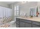 Bathroom featuring a shower/tub with floral curtain, gray vanity, and shutters letting in natural light at 3873 Newhall St, Mount Pleasant, SC 29466