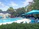 Community pool surrounded by palm trees, lounge chairs, umbrellas and small white cabanas at 45 Sycamore Ave # 116, Charleston, SC 29407