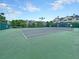 A sunny tennis court area surrounded by green fences and residential buildings at 45 Sycamore Ave # 116, Charleston, SC 29407