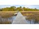 A wooden dock extends over the water, leading to a boat under a blue sky at 630 Cain Dr, Mount Pleasant, SC 29464