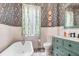 Elegant bathroom featuring a clawfoot tub, decorative wallpaper, and mint green vanity at 78 Society St, Charleston, SC 29401