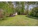 Large, green backyard showcasing manicured landscaping and a small shed among tall trees at 9447 Harroway Rd, Summerville, SC 29485