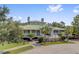 An impressive clubhouse with a green metal roof, white columns, and palm trees under a sunny sky at 9447 Harroway Rd, Summerville, SC 29485