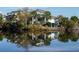 Stunning waterfront home reflecting on the lake, surrounded by lush greenery and palm trees at 1 Battery Park Rd, Edisto Island, SC 29438