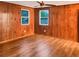 Bedroom with wood paneled walls, new hardwood floors, and bright windows overlooking the yard at 1085 Russellville Rd, Saint Stephen, SC 29479