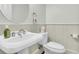 Elegant bathroom with a pedestal sink, white wainscoting, round mirror, and modern fixtures at 12 Leeann Ln, Mount Pleasant, SC 29464