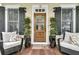 Stylish front entrance with a wooden door, decorative plants, and comfortable seating on the porch at 12 Leeann Ln, Mount Pleasant, SC 29464