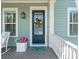 Charming front porch with a decorated blue door, flower pot, and a rocking chair at 1479 Mossy Branch Way, Mount Pleasant, SC 29464
