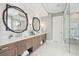 A luxurious bathroom with double vanity, round mirrors, marble tile, and a glass-enclosed shower at 1529 Tomato Farm Cir, Mount Pleasant, SC 29464