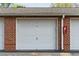 Attached one-car garage with red brick facade and a painted door at 1597 Cambridge Lakes Dr # 303E, Mount Pleasant, SC 29464