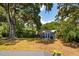 Backyard with a blue shed with white trim and an American flag sitting on a grass lawn under the shade of a tree at 1756 Mchenry Ave, Charleston, SC 29412