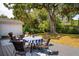 Backyard patio with round table and chairs sitting on a blue and white rug under a large tree with a covered area in the background at 1756 Mchenry Ave, Charleston, SC 29412