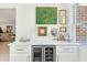 Stylish bar area with a beverage cooler, white cabinets, and decorative wall art at 1756 Mchenry Ave, Charleston, SC 29412