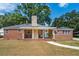 Charming brick home featuring a welcoming front porch, lush landscaping, and a classic American flag at 1756 Mchenry Ave, Charleston, SC 29412