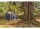 View of a charming backyard shed with a patriotic American flag and seating, surrounded by lush greenery at 1756 Mchenry Ave, Charleston, SC 29412
