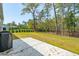 Backyard with patio, grill, green grass, and a wooded view beyond a black metal fence at 2036 Yaupon Way, Johns Island, SC 29455