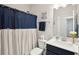 This bathroom features a shower with a blue shower curtain, a white sink, and a dark blue vanity at 2036 Yaupon Way, Johns Island, SC 29455