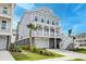 Two story coastal style home, with a large garage and white railings, lush landscaping and palm trees at 2237 Tillage St, Mount Pleasant, SC 29466