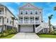 Two-story coastal home boasting a spacious garage, lush greenery, palm trees and an inviting entryway at 2237 Tillage St, Mount Pleasant, SC 29466