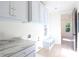 Laundry room with white cabinets and trim, marble countertop, bench, and light wood floors at 295 W Coleman Blvd, Mount Pleasant, SC 29464