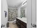Well-lit bathroom featuring a double sink vanity, leafy shower curtain, and neutral tile flooring, offering comfort and functionality at 320 Silverleaf Ln, Moncks Corner, SC 29461