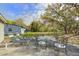 Relaxing backyard patio with lounge chairs and a dining set, set against a backdrop of mature trees and blue skies at 322 Lantana Dr, Charleston, SC 29407