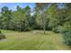 Lush backyard with mature trees, a small bridge, and sprawling lawn at 3378 Von Ohsen Rd, Ladson, SC 29485