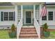 Charming covered front porch with brick steps and green planters leading to the front door at 3378 Von Ohsen Rd, Ladson, SC 29485