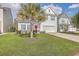 Charming two-story home featuring a well-manicured lawn, a palm tree, and a striking pink front door at 353 Dunlin Dr, Summerville, SC 29486