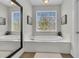 Bright bathroom featuring a large soaking tub, a window with blinds, and a big mirror at 3734 St Ellens Dr, Mount Pleasant, SC 29466