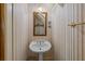 Charming powder room featuring striped wallpaper, pedestal sink, and decorative mirror at 377 Lofton Ct, McClellanville, SC 29458
