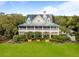 Beautiful exterior view of home with a metal roof, spacious porch, lush landscaping and mature trees at 377 Lofton Ct, McClellanville, SC 29458