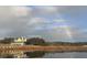 Charming waterfront home with a wraparound porch, surrounded by trees, with a rainbow in the sky at 377 Lofton Ct, McClellanville, SC 29458