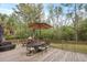 Outdoor deck area features dining table and chair set with umbrella, lounge seating, and wooded views at 4204 Magnolia Ct, North Charleston, SC 29420